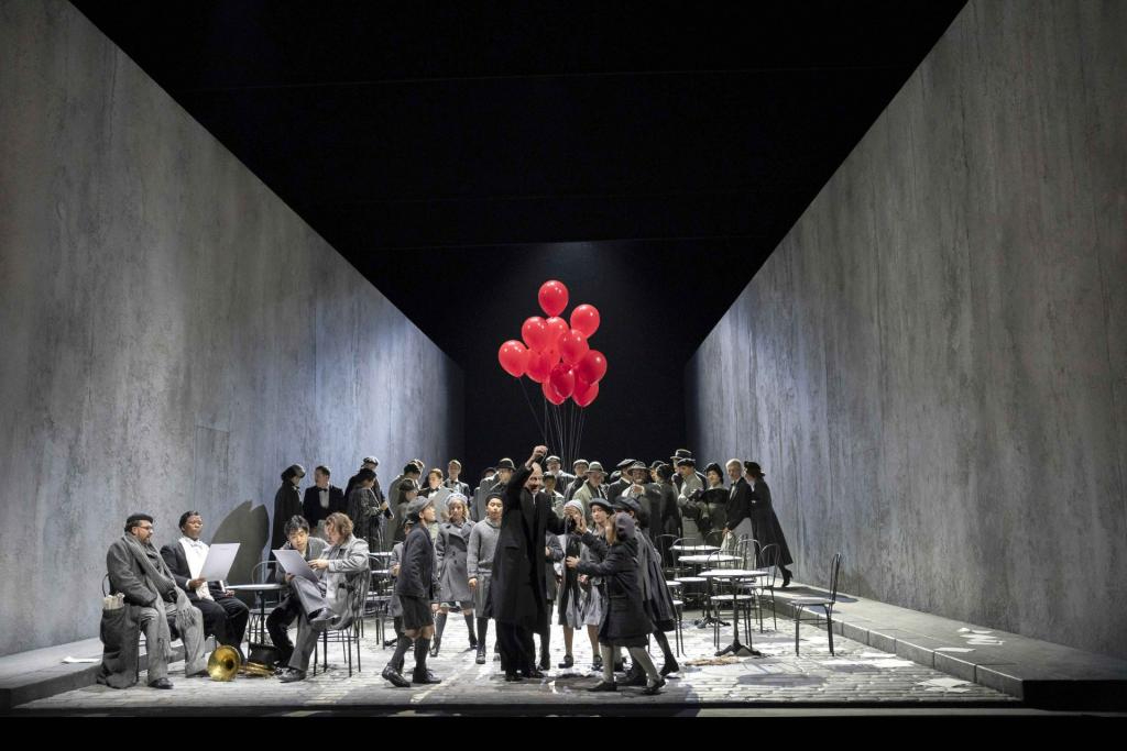 Full cast on grey set with red balloons.
